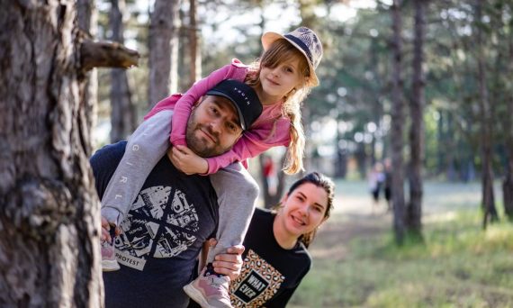 A joyful family enjoying a playful day in a sunlit forest park, capturing the essence of togetherness.